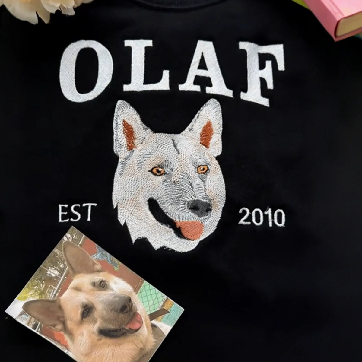 Black sweatshirt with OLAF in white letters and an embroidered white shepherd dog, EST 2010