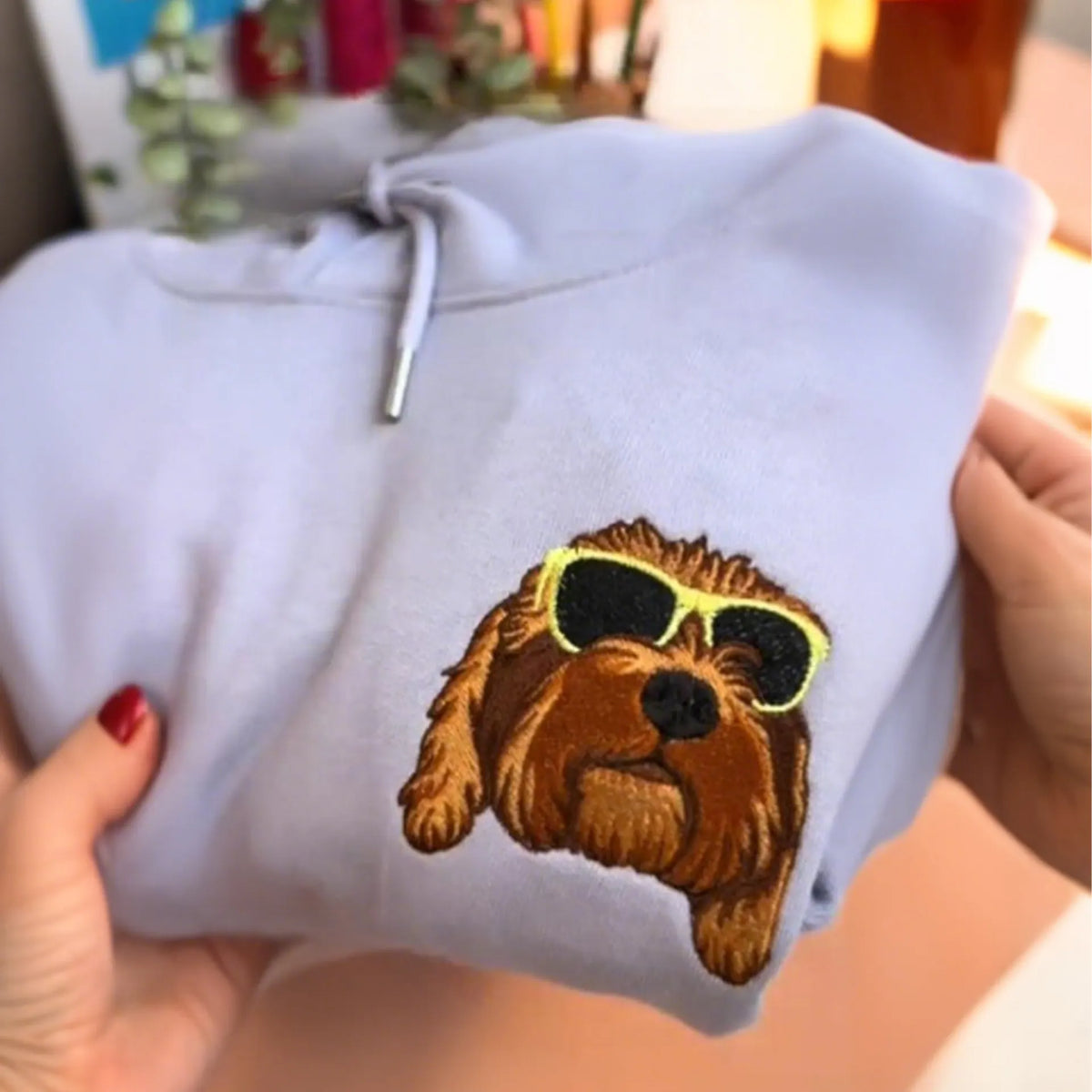 Doodle wearing yellow sunglasses embroidered on a lavender hoodie