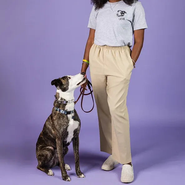 Woman wearing a white tee with a left chest line art dog portrait, standing with her brindle dog