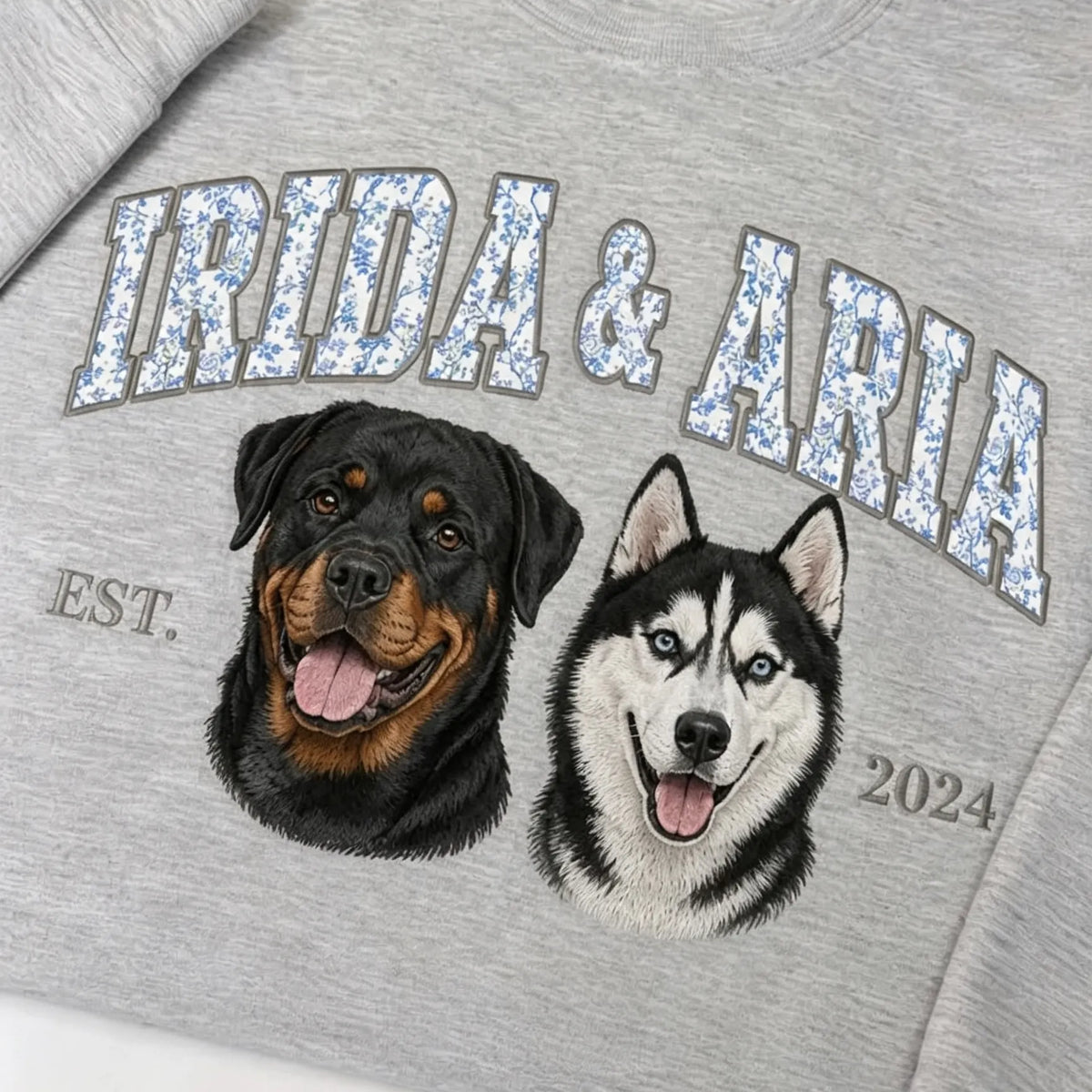 Gray sweatshirt with IRIDA & ARIA in floral letters above an embroidered rottweiler and husky