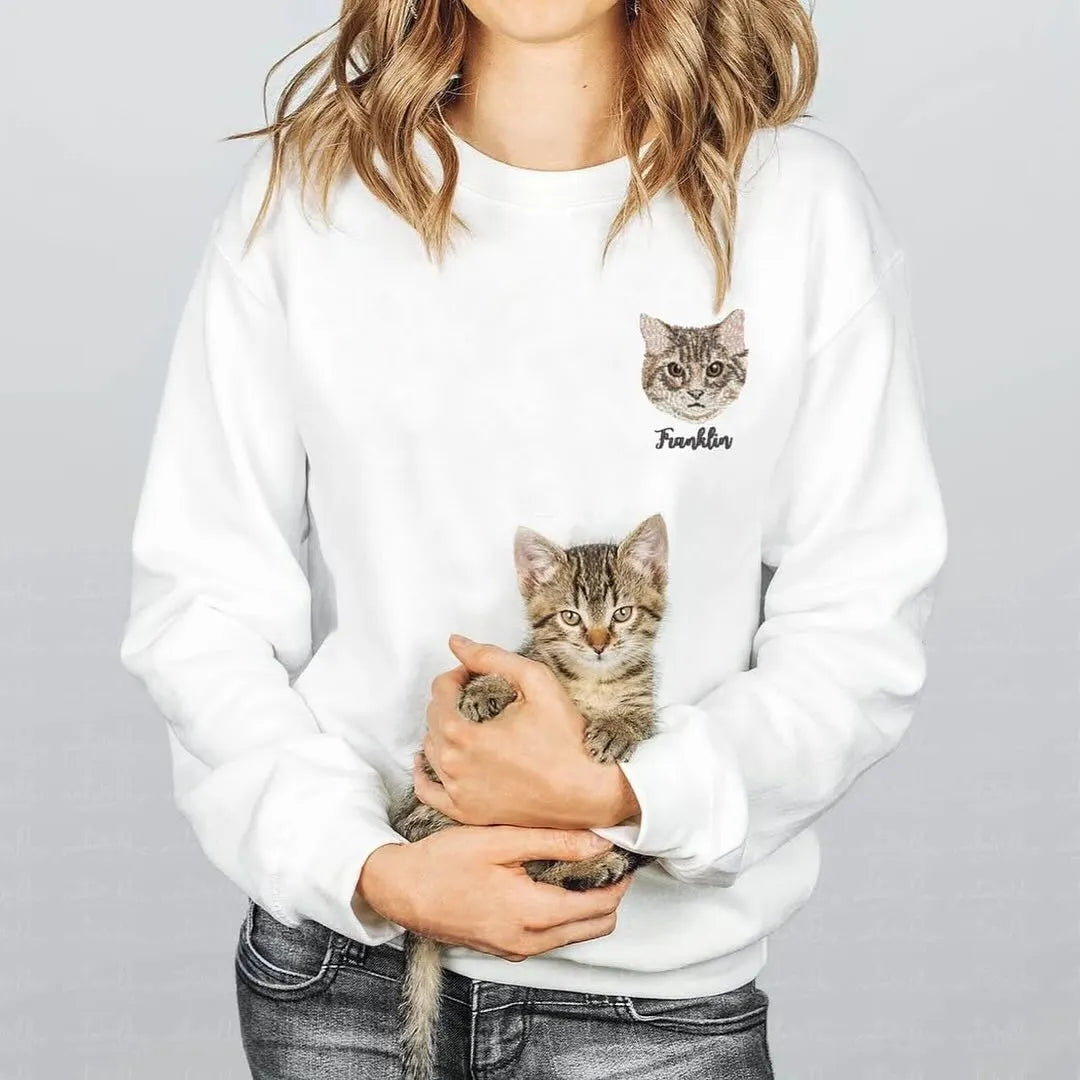 Woman holding a kitten and wearing a white sweatshirt with the cat's embroidered face and name Franklin