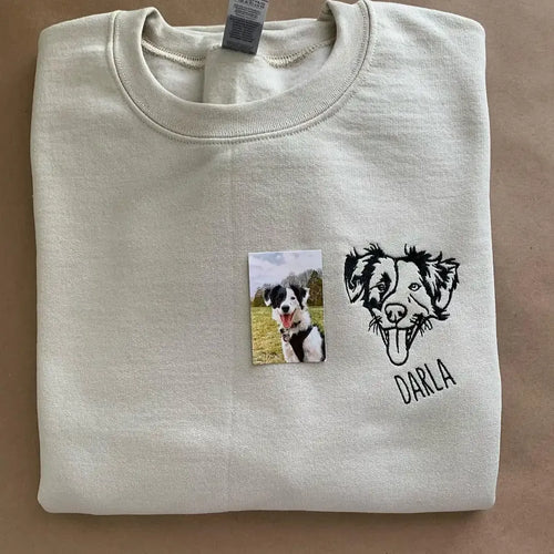 Line art dog portrait embroidered on the chest of a sand sweatshirt with the name Darla, shown next to the original photo