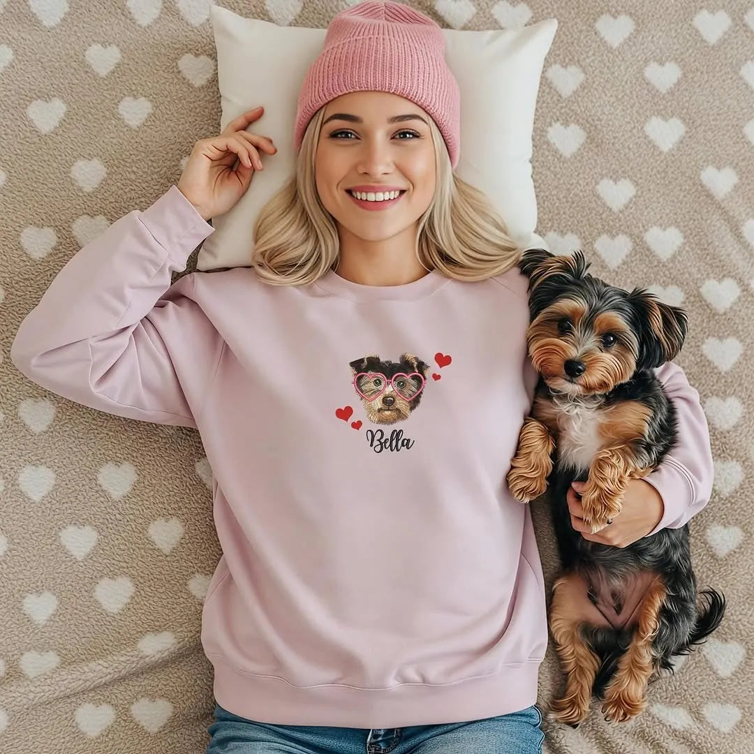 Woman on a bed with her Yorkie, wearing a pink sweatshirt with the dog's face, hearts and the name Bella