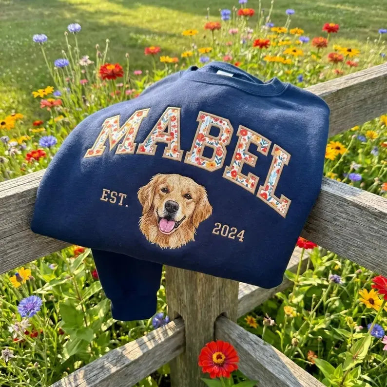 Cream sweatshirt with DAISY in red floral appliqué letters above an embroidered shiba inu