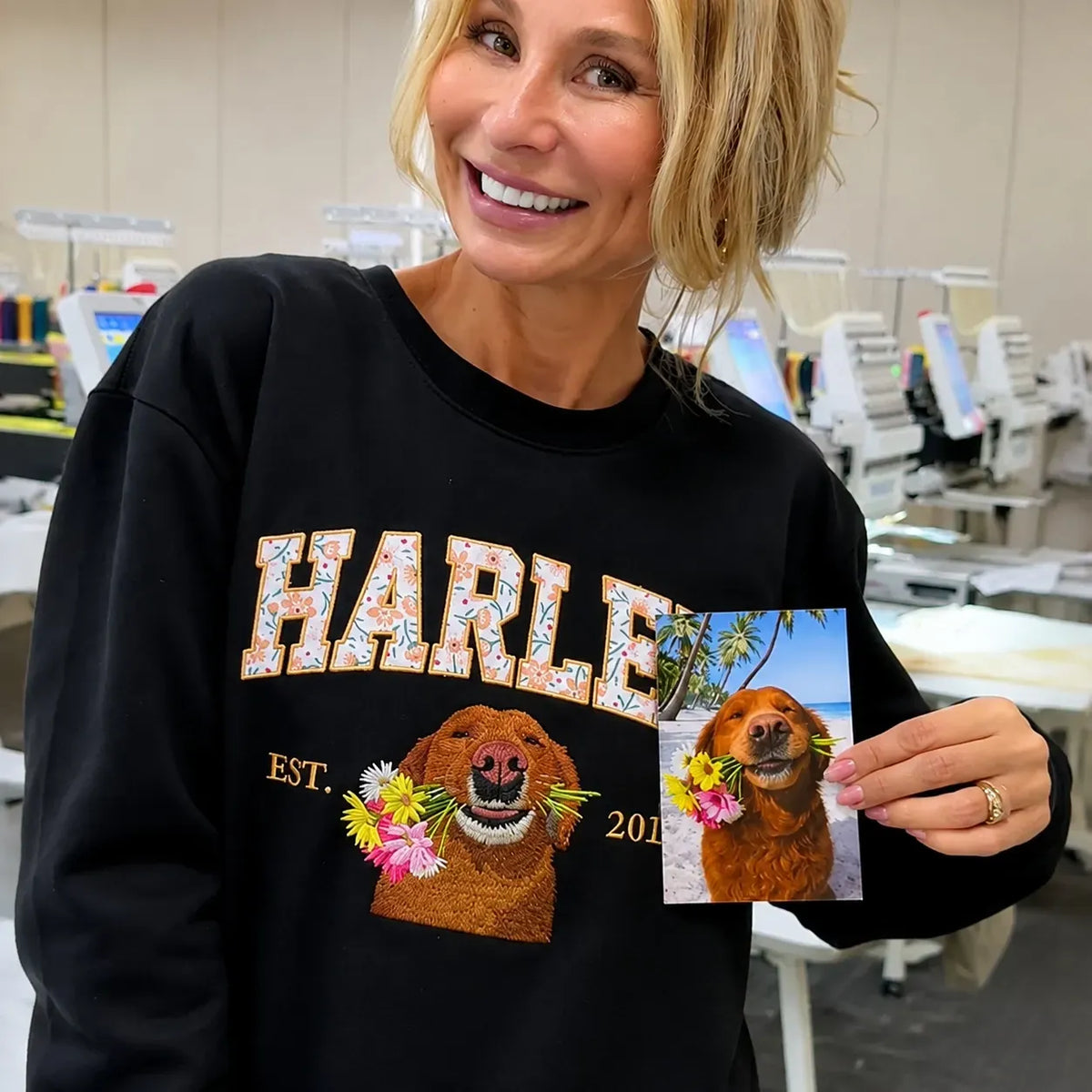 Woman wearing a black sweatshirt with floral appliqué name letters and an embroidered golden retriever