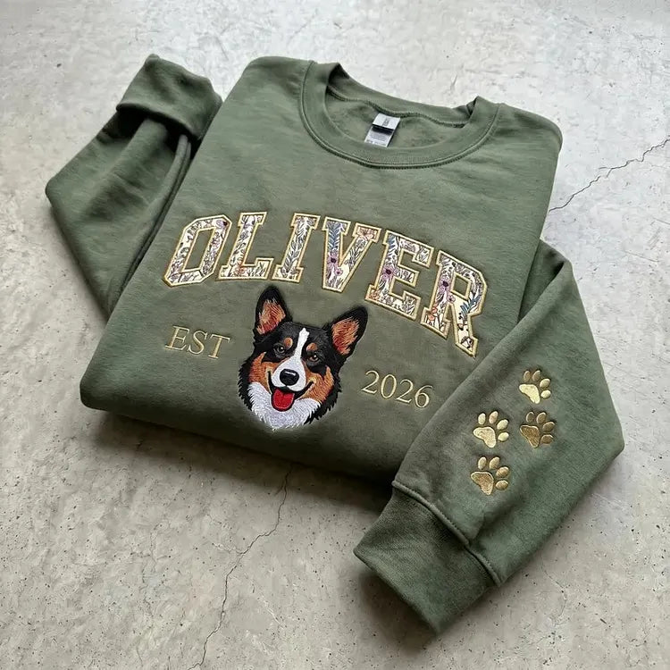 Olive sweatshirt with OLIVER in floral appliqué letters above an embroidered corgi and EST 2020, paw prints on the sleeve