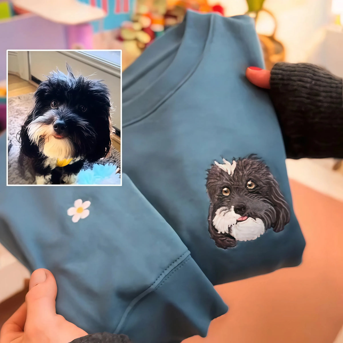 Black and white dog portrait embroidered on a teal sweatshirt with a small daisy on the sleeve