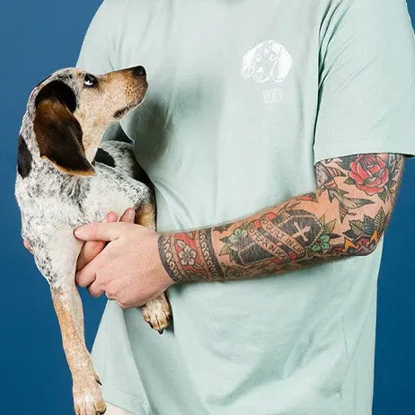Man holding his hound wearing a mint tee with a tone-on-tone embroidered dog outline