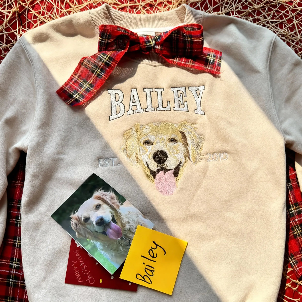 Cream sweatshirt with BAILEY and a golden retriever face, wrapped as a holiday gift with a plaid bow
