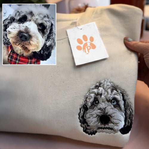 Gray poodle mix face embroidered in detailed black and gray thread on a sand sweatshirt