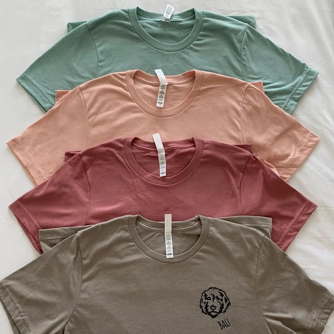 Stack of four vintage pepper color tees in sage, peach, mauve and olive with a doodle line art portrait