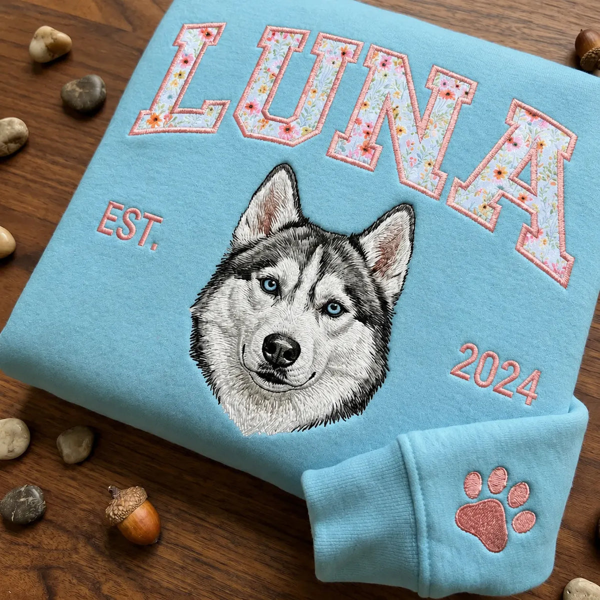 Navy sweatshirt with MABEL in floral letters and an embroidered golden retriever, hung on a garden fence
