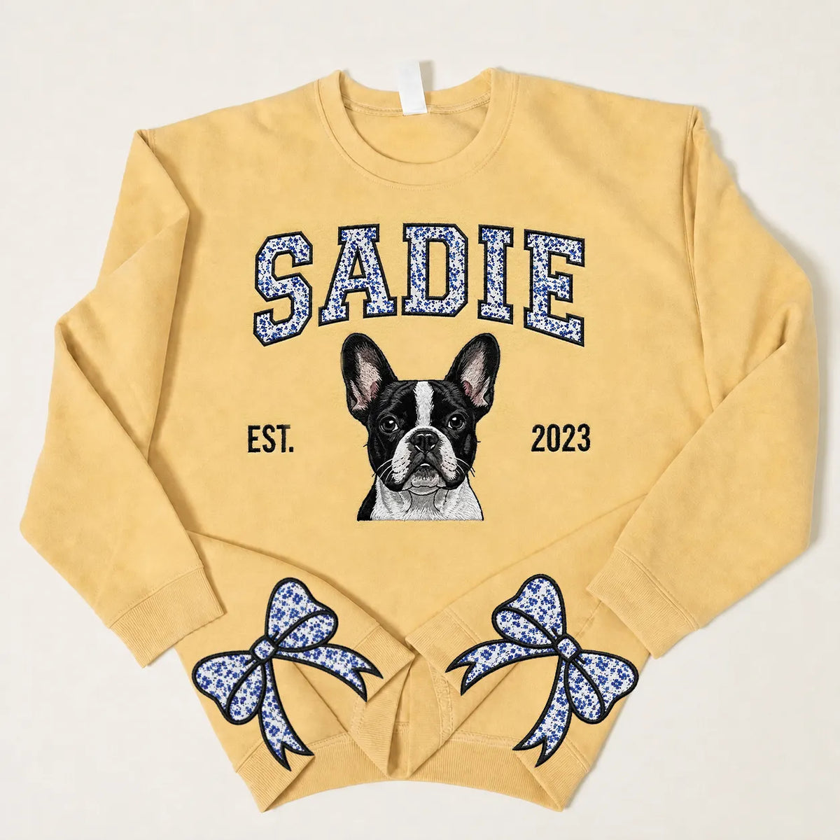 Mustard sweatshirt with SADIE in blue floral letters above an embroidered Boston terrier and blue floral bows on the cuffs