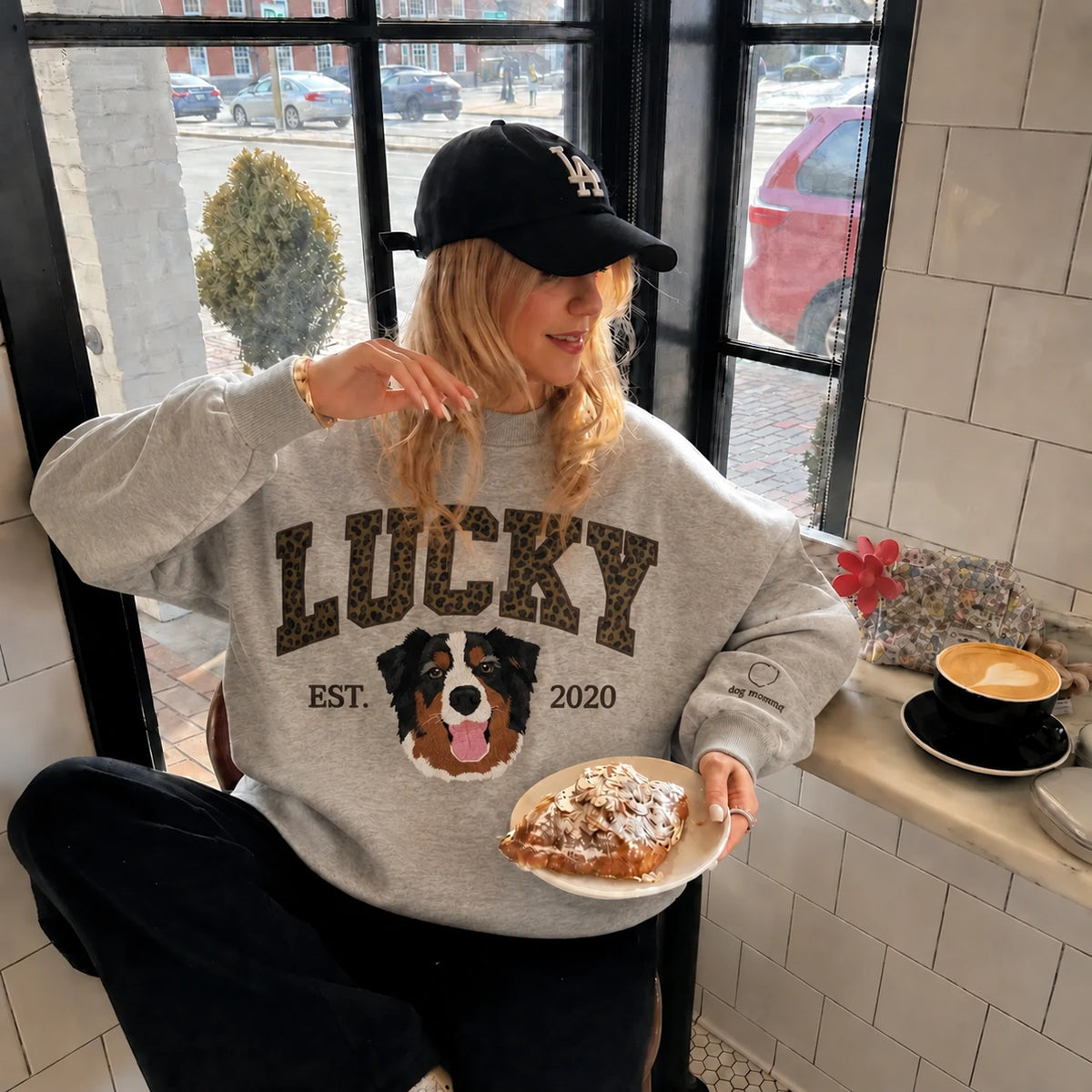 Woman in a gray mockneck sweatshirt with LUCKY in leopard print letters above an embroidered Bernese mountain dog