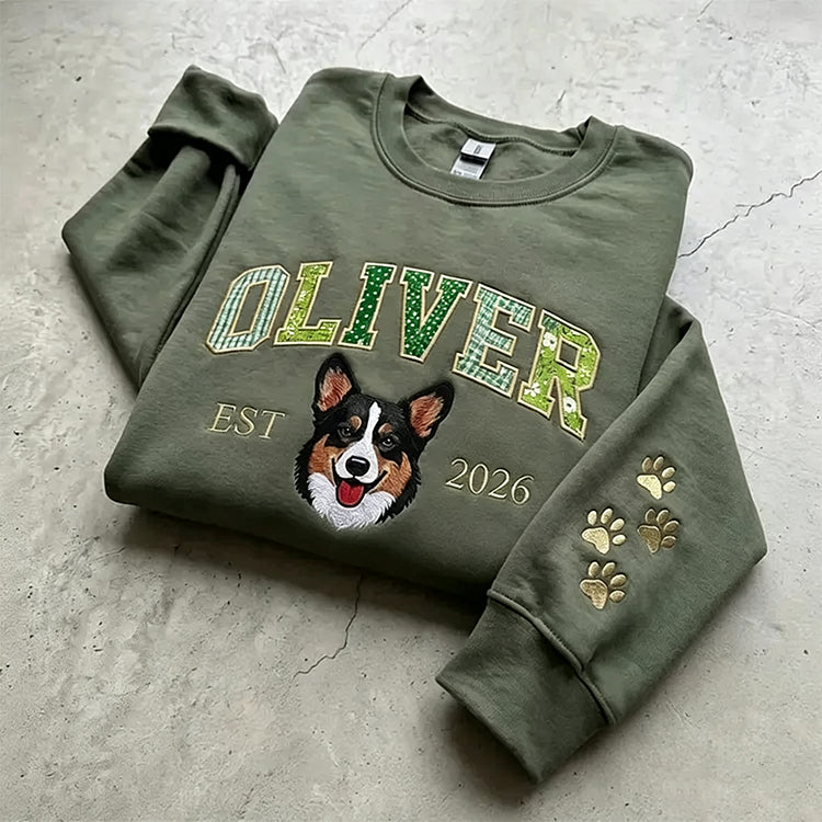 Olive sweatshirt with OLIVER in green patchwork letters above an embroidered corgi, paws on the sleeve
