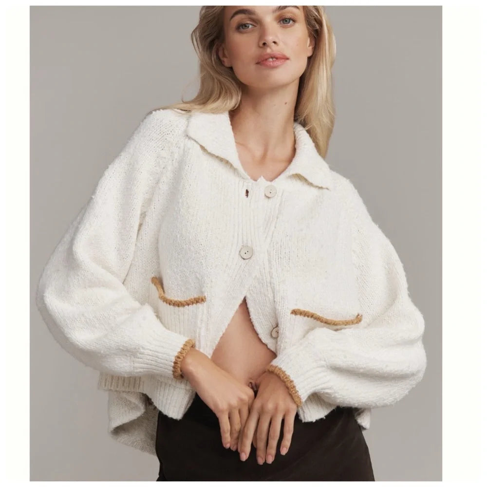 Woman wearing an ivory oversized collared cardigan with contrast-trim patch pockets, front view