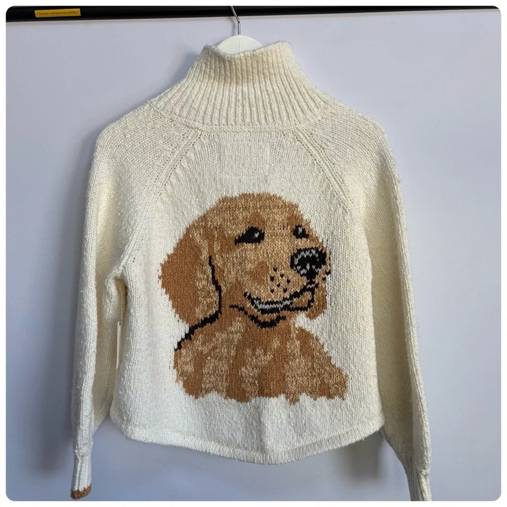 Ivory cardigan with a knitted golden retriever portrait, hanging on a wall