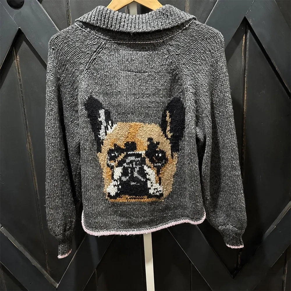 Gray cardigan with a knitted French bulldog portrait, hanging on a dark door