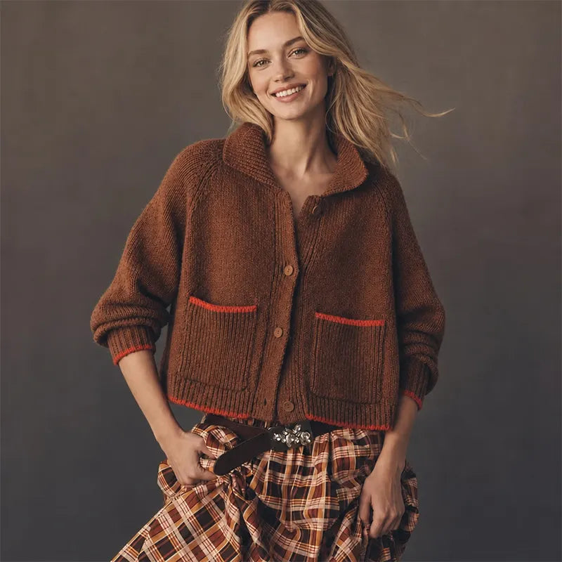 Woman wearing a rust brown collared cardigan with red-trimmed patch pockets