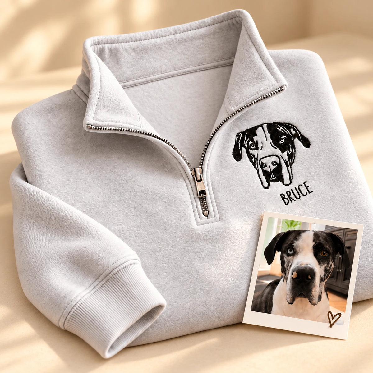 Light gray quarter zip sweatshirt with a black line art Great Dane portrait and the name BRUCE, next to the original pet photo