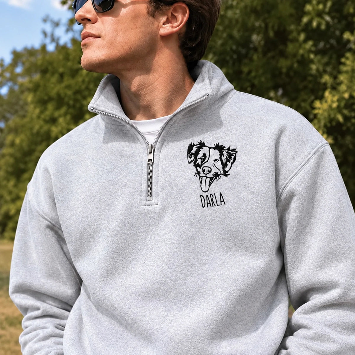 Man wearing a heather gray quarter zip sweatshirt with a line art dog portrait and the name DARLA
