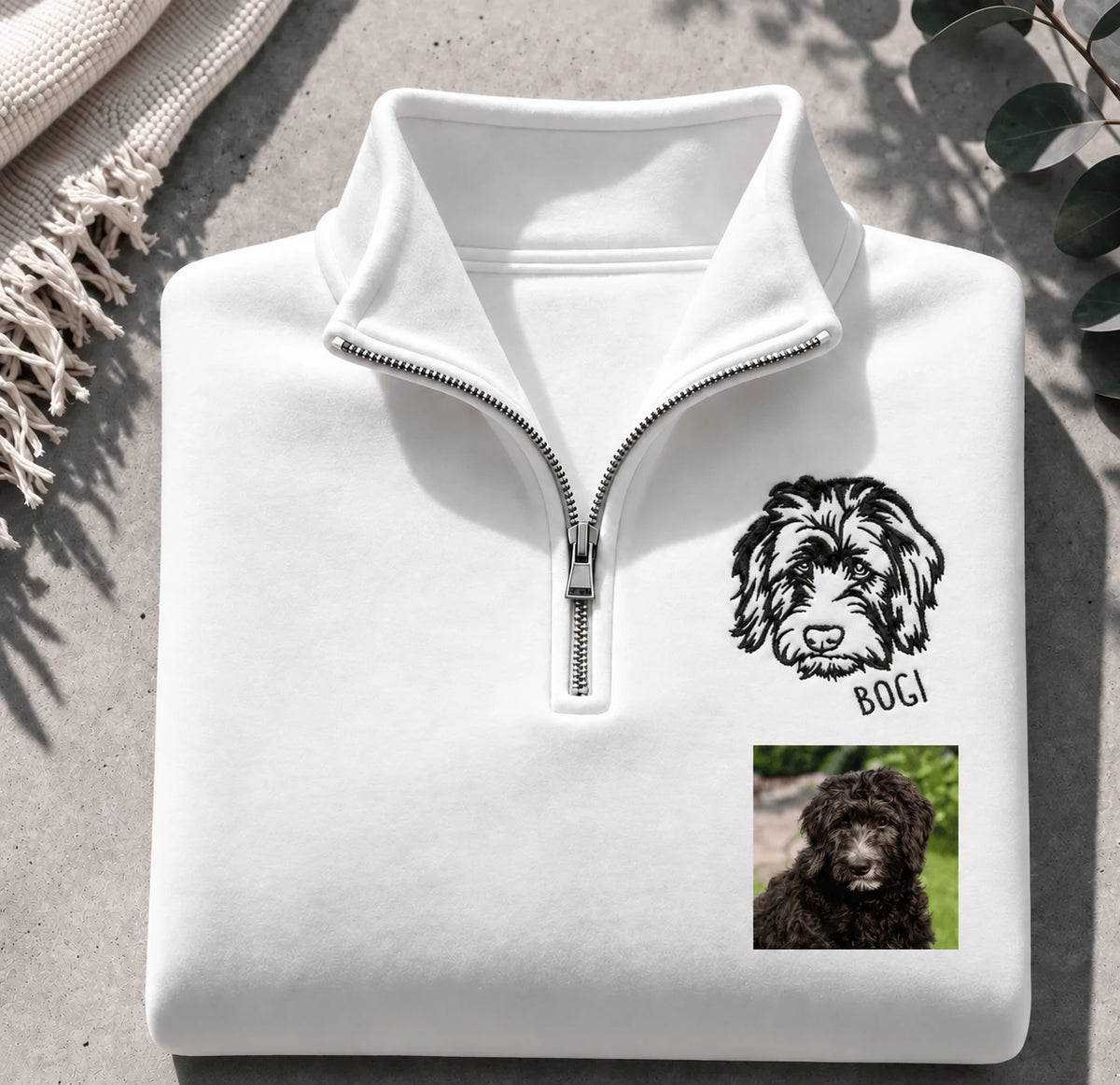 Folded white quarter zip sweatshirt with a line art doodle portrait named BOGI and the original photo