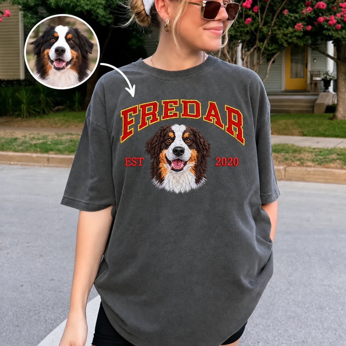 Woman outdoors wearing a charcoal washed T-shirt with red and gold FREDAR lettering, a colorful embroidered dog portrait, EST 2020, and a small circular original dog photo inset